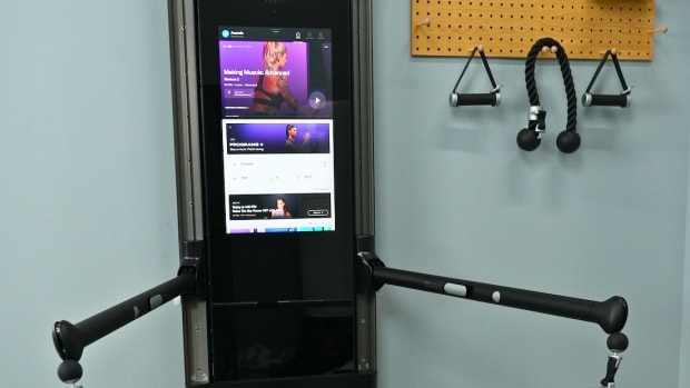 A Tonal home workout system, with touchscreen, adjustable arms and attachments.